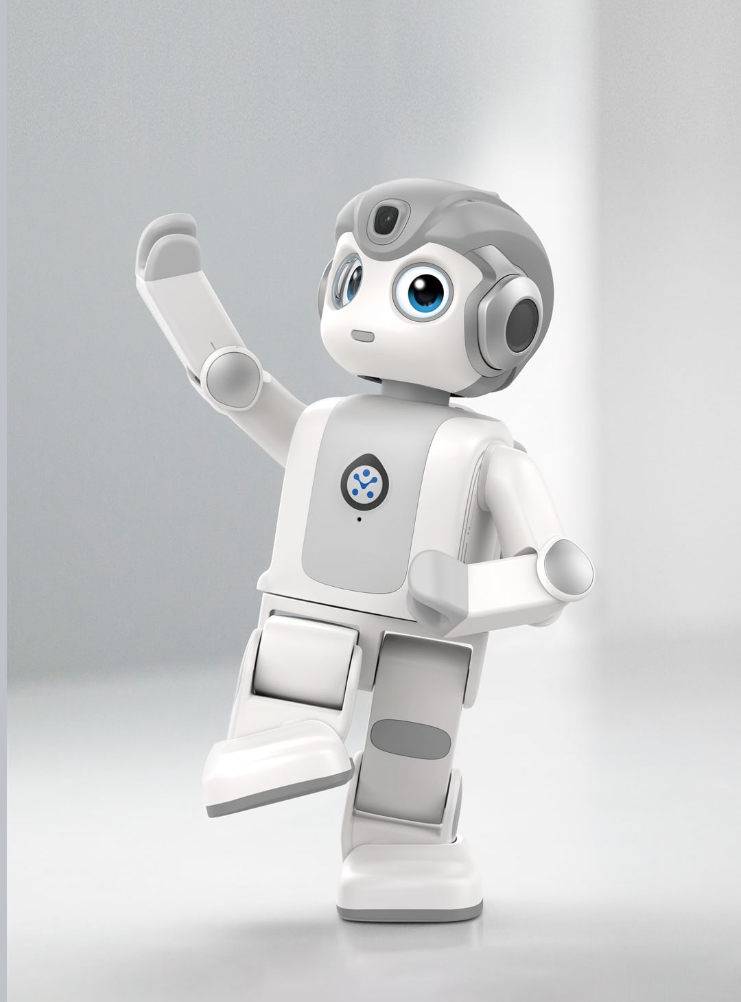 หุ่นยนต์ humanoid ตั้งโต๊ะ UBTech Alpha Mini ยกแขนขึ้นข้างหนึ่ง มีกล้องที่หน้าผากและดวงตา LCD สีฟ้า